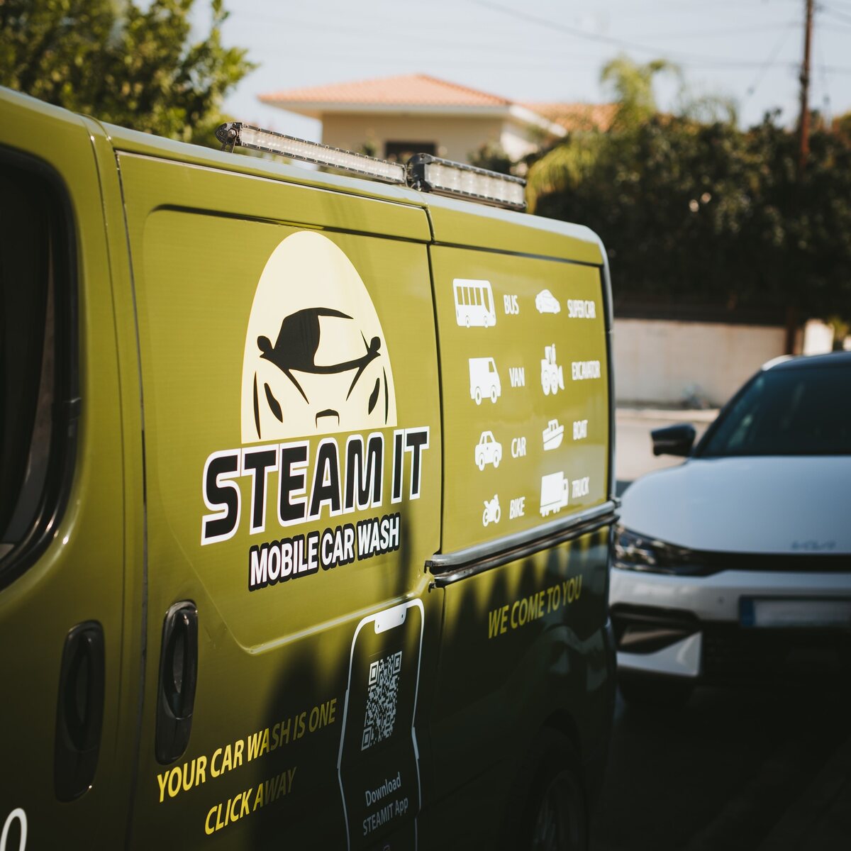 Branded Steamit mobile car-wash vehicle beside a customer car